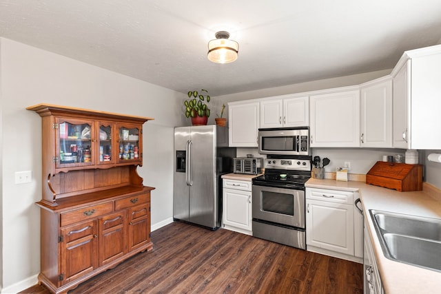 kitchen with sink, white cabinetry, dark wood-type flooring, and appliances with stainless steel finishes