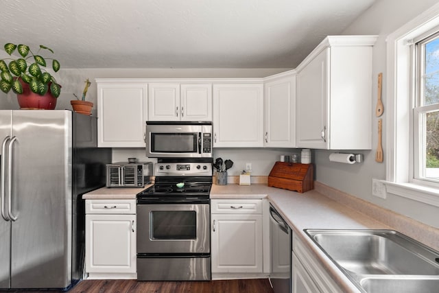 kitchen with a healthy amount of sunlight, dark hardwood / wood-style flooring, white cabinets, and stainless steel appliances