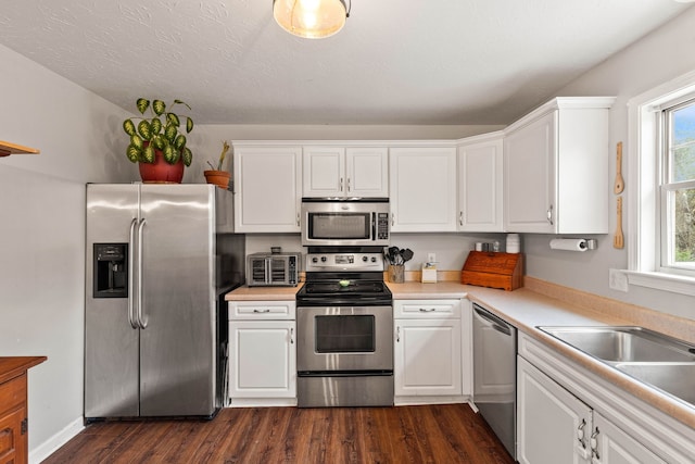 kitchen featuring white cabinets, dark hardwood / wood-style flooring, stainless steel appliances, and a textured ceiling