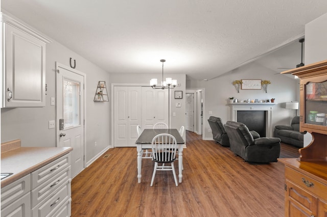 dining area with vaulted ceiling, light hardwood / wood-style flooring, a textured ceiling, and an inviting chandelier