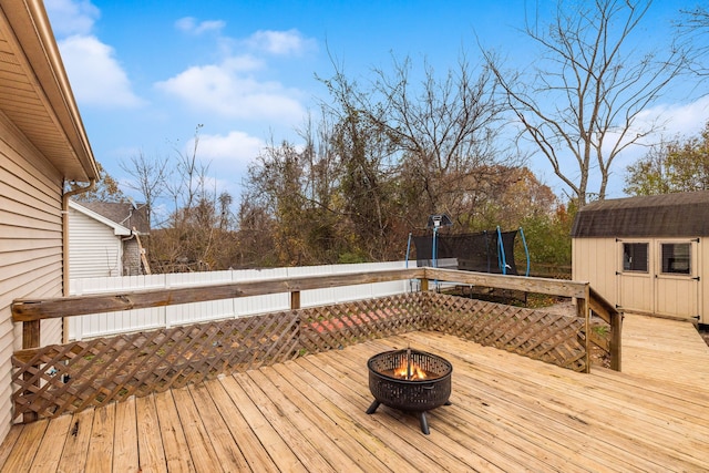 wooden terrace featuring a trampoline and a fire pit