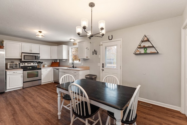 dining room with a chandelier, sink, and dark wood-type flooring