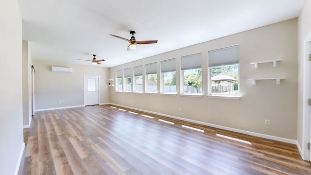 empty room with hardwood / wood-style flooring, an AC wall unit, and ceiling fan