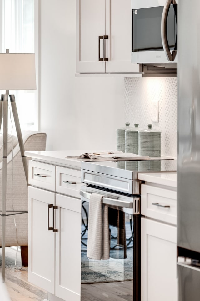 kitchen with white cabinets, appliances with stainless steel finishes, and light hardwood / wood-style floors