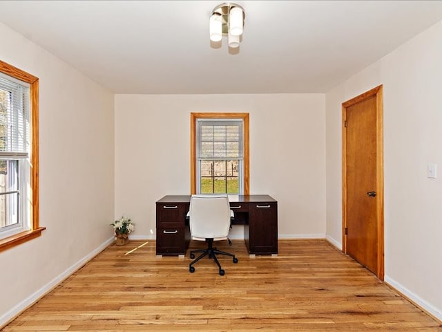 office area with light hardwood / wood-style flooring and a healthy amount of sunlight