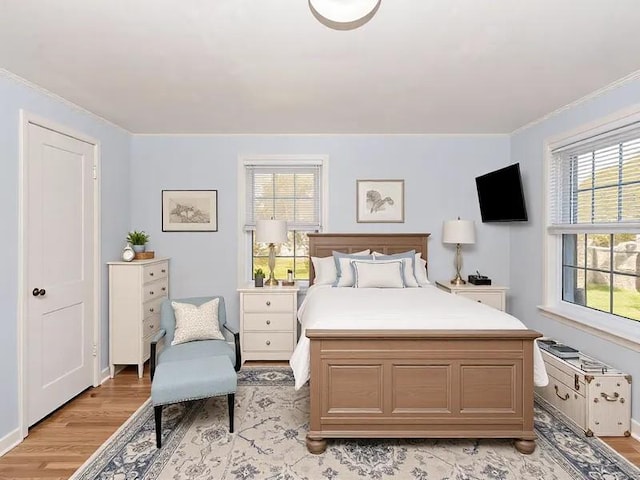 bedroom featuring ornamental molding, light hardwood / wood-style floors, and multiple windows