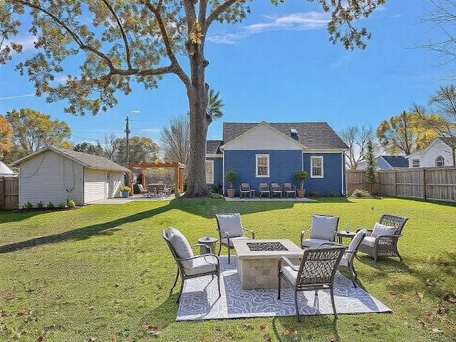 rear view of house with an outdoor fire pit, an outdoor structure, a yard, and a patio area