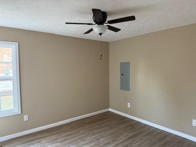 unfurnished room with ceiling fan, dark wood-type flooring, a textured ceiling, and electric panel