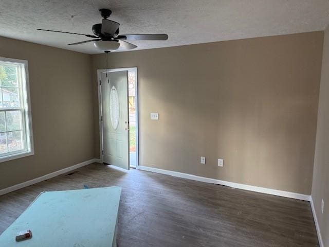 unfurnished room featuring ceiling fan, dark hardwood / wood-style floors, and a healthy amount of sunlight