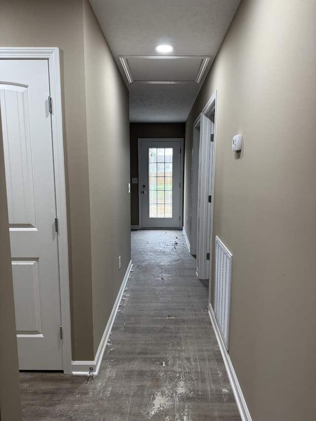 corridor with baseboards, visible vents, and wood finished floors