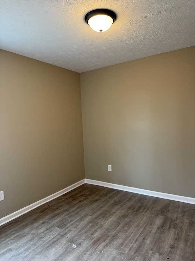 unfurnished room with dark wood-style floors, a textured ceiling, and baseboards