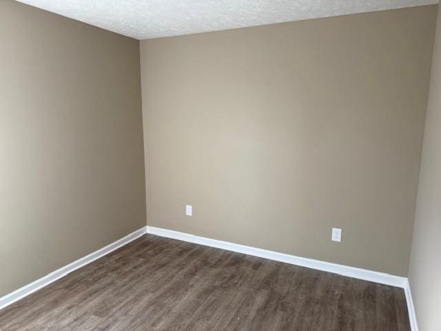 unfurnished room with baseboards, a textured ceiling, and dark wood-style flooring