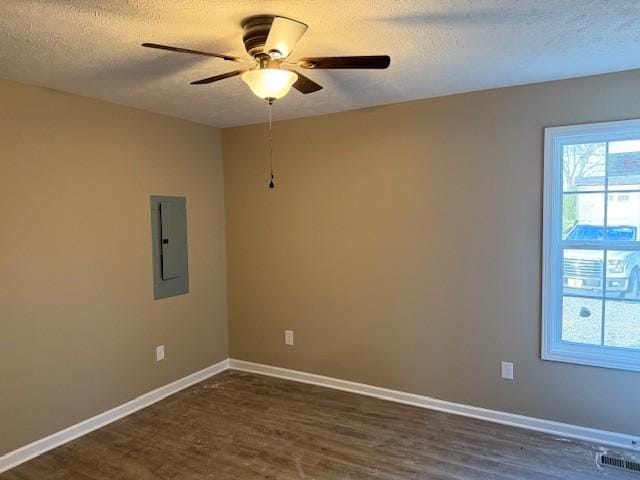 spare room featuring baseboards, visible vents, electric panel, dark wood-style flooring, and ceiling fan
