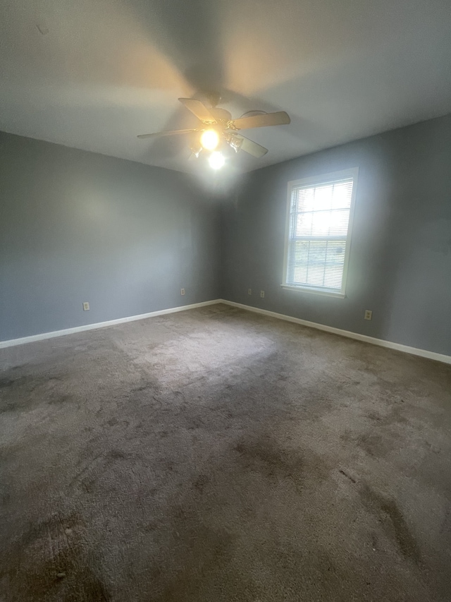 spare room featuring ceiling fan and dark carpet