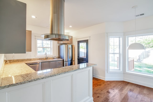 kitchen featuring white cabinets, light stone counters, appliances with stainless steel finishes, and light hardwood / wood-style flooring