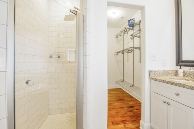 bathroom with tiled shower, vanity, and hardwood / wood-style flooring