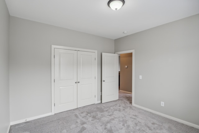 unfurnished bedroom featuring light carpet and a closet