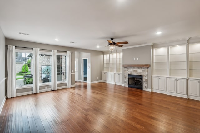 unfurnished living room featuring ceiling fan, wood-type flooring, a fireplace, and ornamental molding