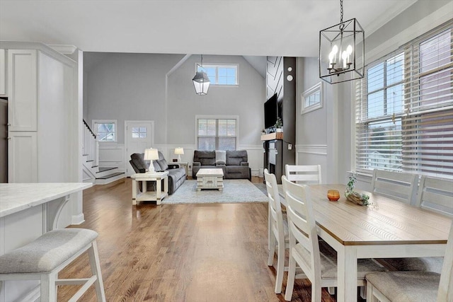 dining area with a high ceiling, hardwood / wood-style flooring, and an inviting chandelier