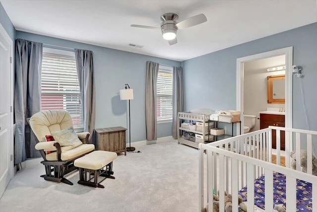 bedroom featuring ceiling fan, a crib, light carpet, and multiple windows