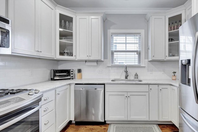 kitchen featuring backsplash, white cabinetry, sink, and appliances with stainless steel finishes