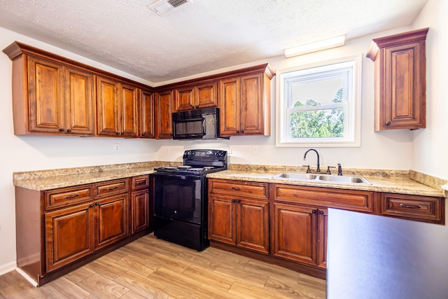 kitchen featuring sink, light stone counters, light hardwood / wood-style floors, a textured ceiling, and black appliances