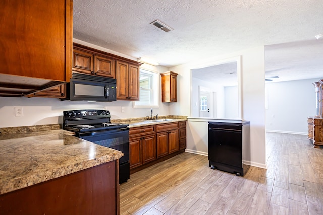 kitchen with light hardwood / wood-style flooring, black appliances, a textured ceiling, and sink