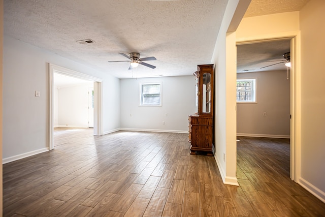 unfurnished living room featuring dark hardwood / wood-style flooring, a healthy amount of sunlight, and a textured ceiling