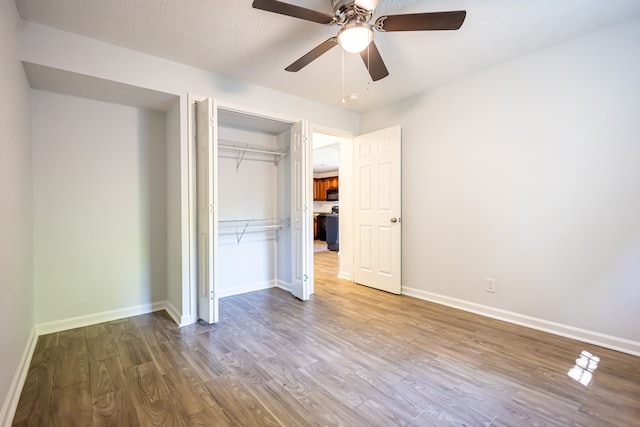 unfurnished bedroom with ceiling fan, wood-type flooring, a textured ceiling, and a closet