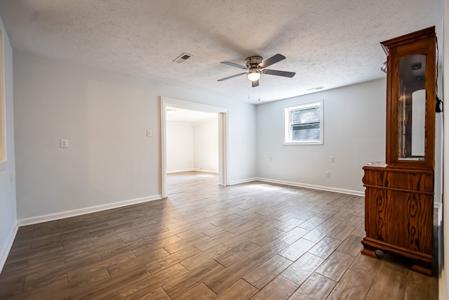 unfurnished room featuring a textured ceiling, ceiling fan, and dark wood-type flooring