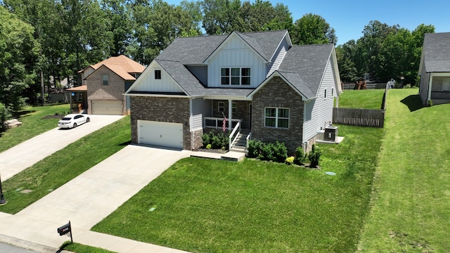 craftsman-style house with a garage, covered porch, central air condition unit, and a front lawn