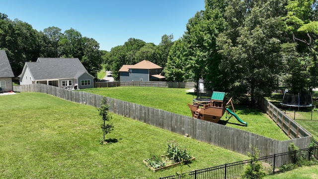 view of yard featuring a trampoline, a playground, and a fenced backyard