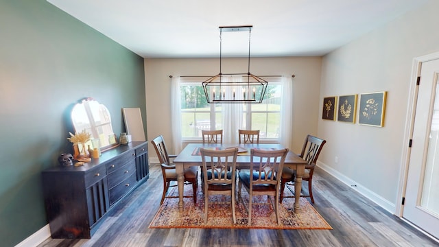 dining area featuring dark wood-type flooring, a chandelier, and baseboards