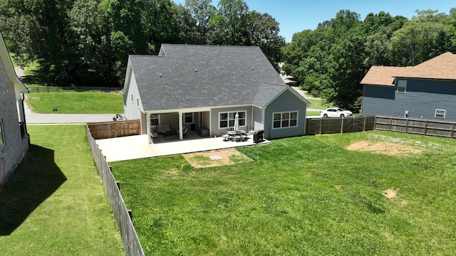 rear view of property with a patio, a shingled roof, a lawn, and a fenced backyard