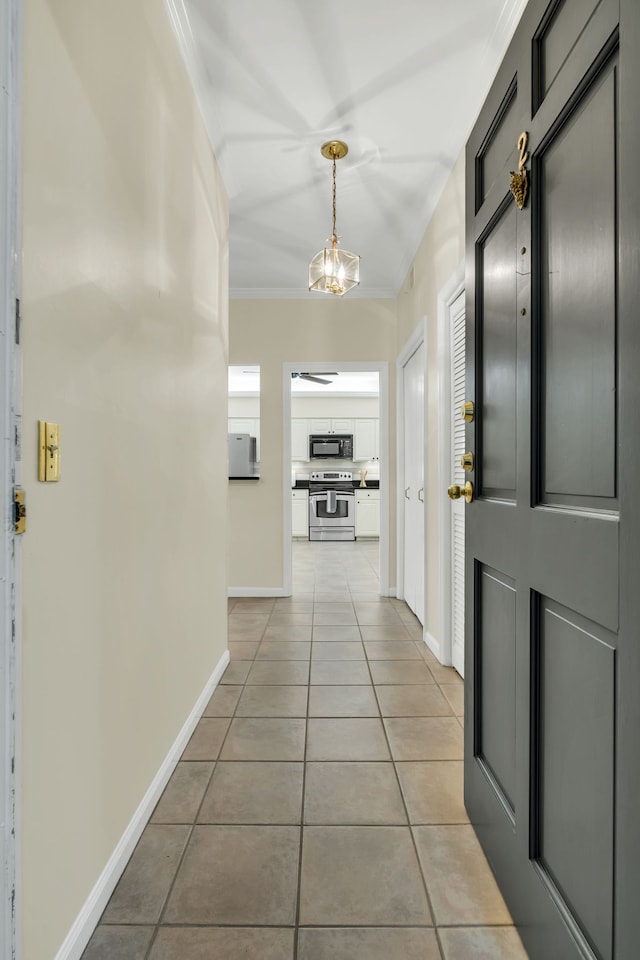 hall with light tile patterned floors, crown molding, and a chandelier