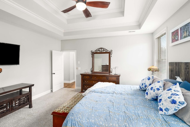 carpeted bedroom featuring a raised ceiling, ceiling fan, and ornamental molding