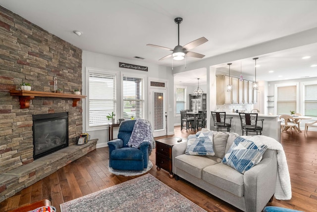 living room with ceiling fan, a fireplace, and dark wood-type flooring