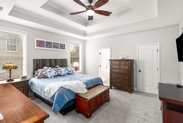 bedroom featuring light carpet, a tray ceiling, ceiling fan, and crown molding