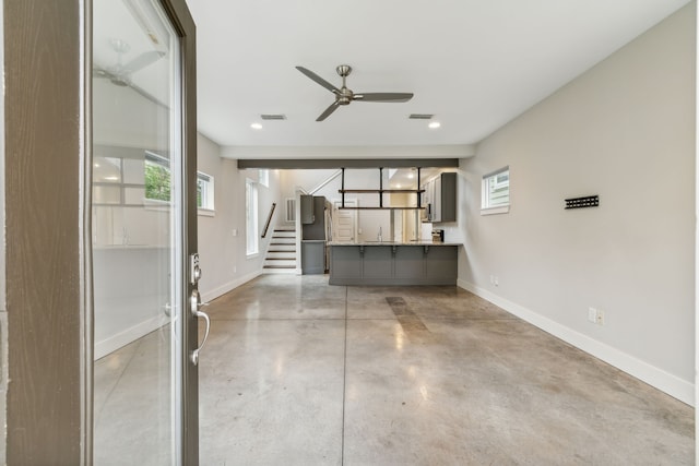 unfurnished living room featuring concrete floors, ceiling fan, and sink