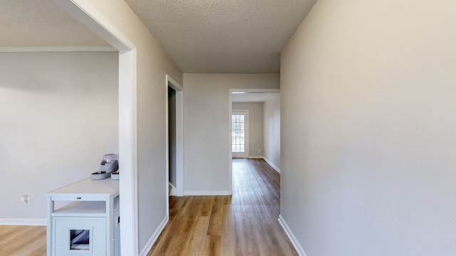 hall featuring light hardwood / wood-style flooring and a textured ceiling