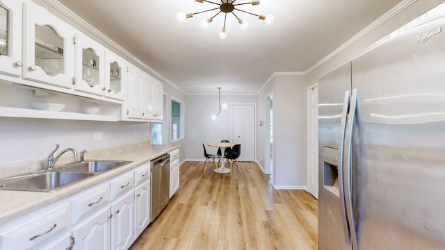 kitchen with white cabinets, sink, hanging light fixtures, ornamental molding, and stainless steel appliances