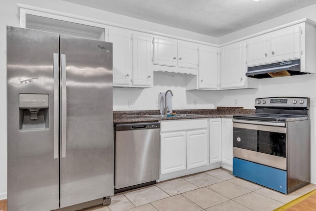 kitchen featuring sink, stainless steel appliances, light tile patterned floors, a textured ceiling, and white cabinets