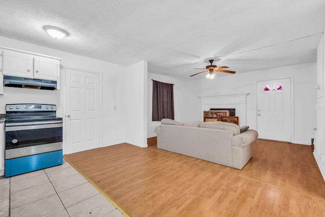 living room featuring a textured ceiling, light hardwood / wood-style floors, and ceiling fan