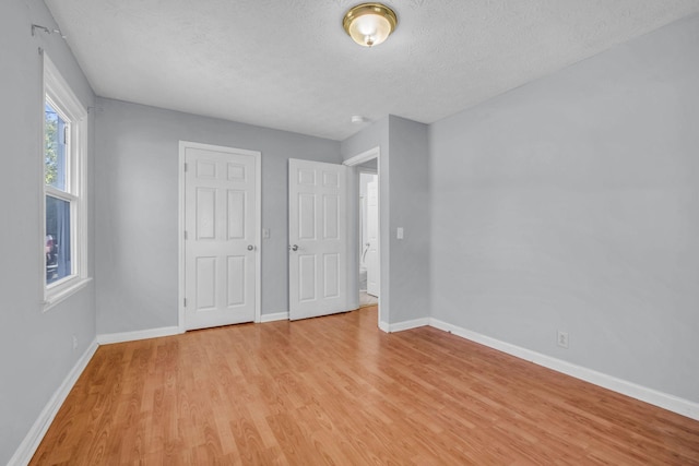 unfurnished bedroom with a textured ceiling and light wood-type flooring