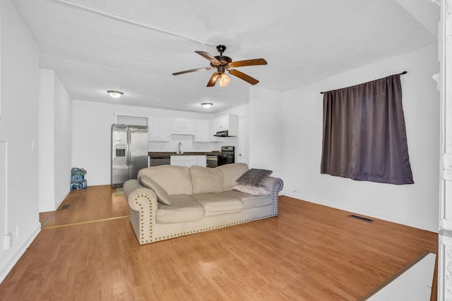 living room with ceiling fan, light wood-type flooring, and sink