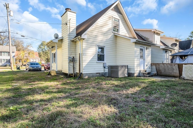 rear view of property with cooling unit and a lawn