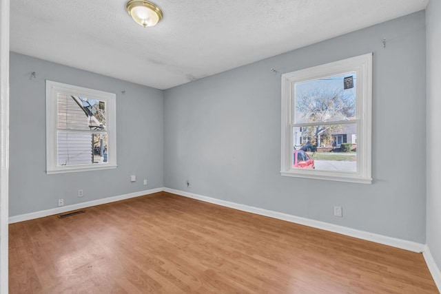 empty room with light hardwood / wood-style floors and a textured ceiling