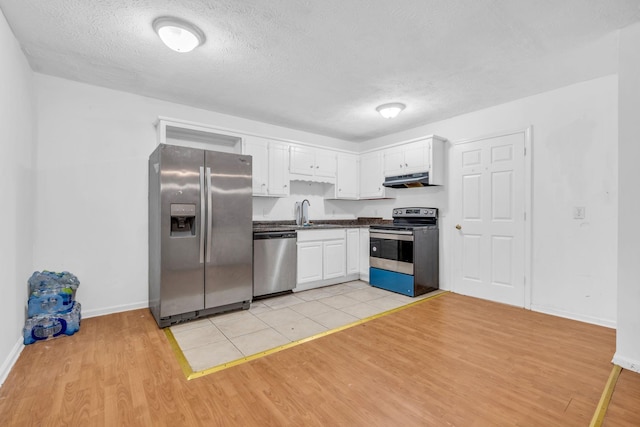 kitchen with white cabinetry, stainless steel appliances, ventilation hood, a textured ceiling, and light wood-type flooring