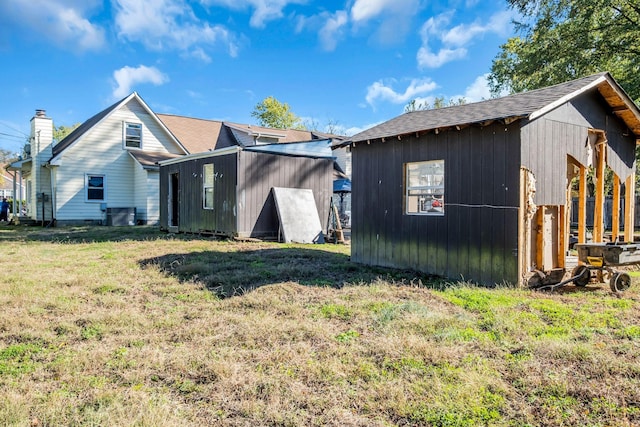 back of property with a lawn and a shed