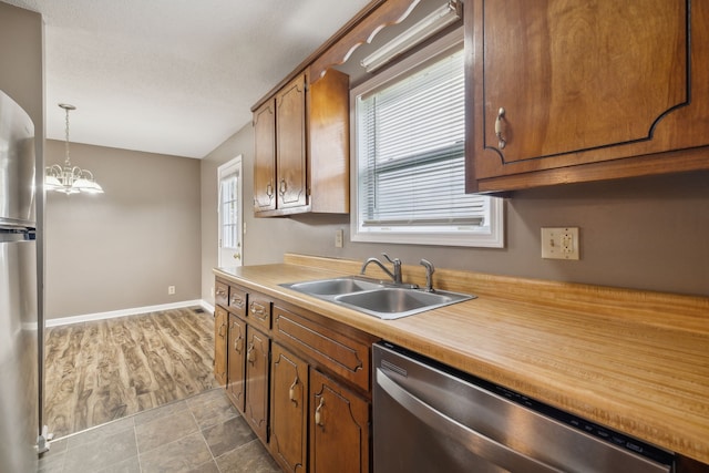 kitchen with plenty of natural light, light wood-type flooring, decorative light fixtures, and appliances with stainless steel finishes